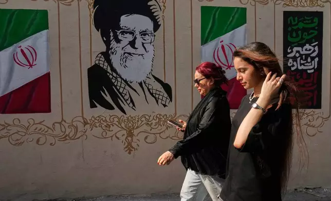 Women walk past a portrait of the late Iranian Supreme Leader Ayatollah Ali Khamenei, who was killed in the U.S. and Israel strike on Feb. 28, and images of the Iranian flag, on a sidewalk in downtown Tehran, Iran, Thursday, Aug. 20, 2026. (AP Photo/Vahid Salemi)