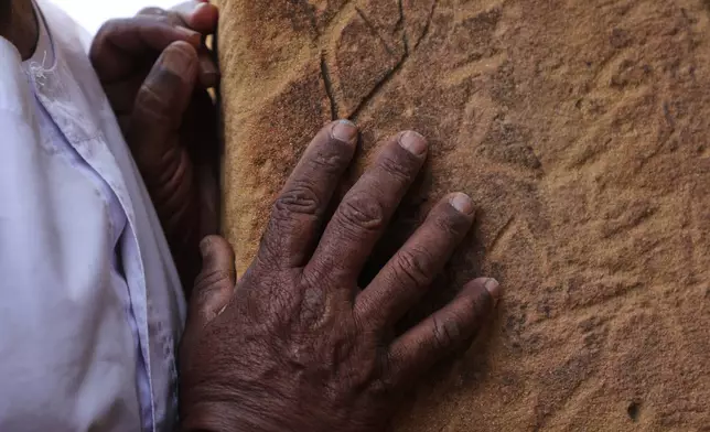 A visitor runs their hand along the stone blocks of a pyramid at the Meroe archaeological site in Bejrawiya, Sudan, Sunday, Aug. 2, 2026. (AP Photo/Mohnd Blal)