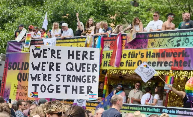 A reveller holds a placard during the Hamburg Pride 2026, the Christopher Street Day (CSD) parade, in Hamburg, Germany, Saturday Aug. 1, 2026. (Georg Wendt/dpa via AP)