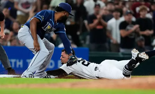 Detroit Tigers' Javier Báez slides safely into third base for a triple ahead of the tag of Tampa Bay Rays third baseman Junior Caminero during the seventh inning of a baseball game Tuesday, Aug. 25, 2026, in Detroit. (AP Photo/Paul Sancya)