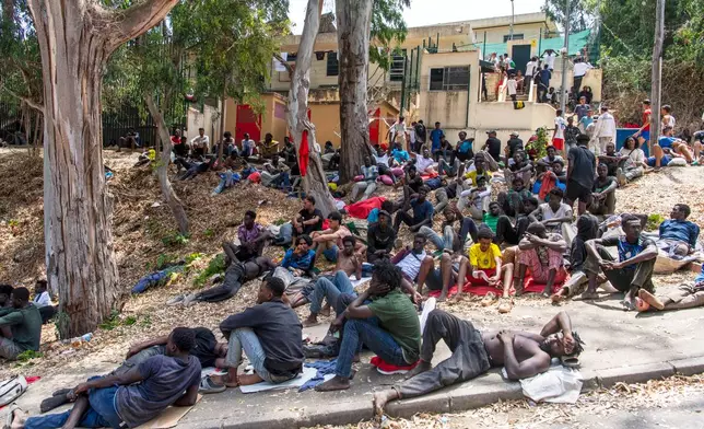 Migrants rest outside the Temporary Center for Immigrants (CETI) after crossing from Morocco into the Spanish enclave of Ceuta, Friday, July 31, 2026. CETI is the Spanish acronym for the migrant reception center. (AP Photo/Antonio Sempere)