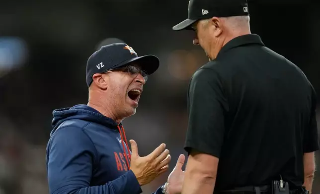 Houston Astros manager Joe Espada, left, argues with first base umpire Lance Barrett (16) during the third inning of a baseball game against the Los Angeles Angels Wednesday, Aug. 19, 2026, in Houston. (AP Photo/David J. Phillip)