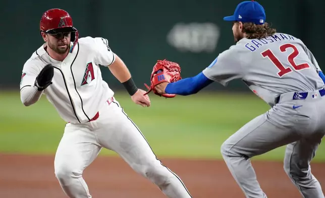 Arizona Diamondbacks' Tim Tawa, left, is tagged out by Chicago Cubs starting pitcher Kevin Gausman (12) during a rundown during the third inning of a baseball game, Monday, Aug. 24, 2026, in Phoenix. (AP Photo/Ross D. Franklin)