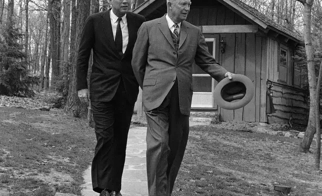 FILE - President John Kennedy and former President Dwight Eisenhower walks along a flagstone path, in perfect step at Camp David, atop of mountain near Thurmont, Maryland on April 22, 1961 after they flew there to discuss the Cuban crisis. In background is one of the lodges at the camp. (AP Photo, File)