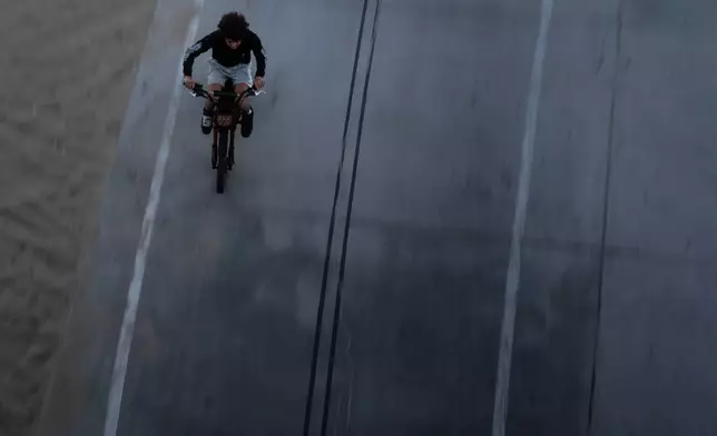 A boy rides an e-bike in Santa Monica, Calif., Monday, Aug. 10, 2026. (AP Photo/Jae C. Hong)