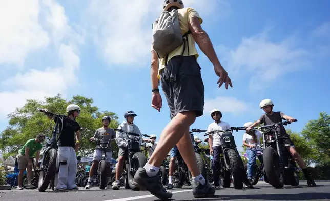 A group of riders listen to an instructor during an e-bike safety and training class Saturday, Aug. 8, 2026, in San Diego. (AP Photo/Gregory Bull)