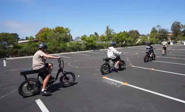 A group of kids ride e-bikes during an e-bike safety and training class Saturday, Aug. 8, 2026, in San Diego. (AP Photo/Gregory Bull)