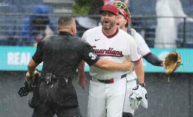 Home plate umpire Jonathan Parra (30) holds back Cleveland Guardians manager Stephen Vogt, center, between catcher Patrick Bailey, left, and pitcher Gavin Williams (32) during an argument in the sixth inning of a baseball game in Cleveland, Sunday, Aug. 2, 2026. (AP Photo/Sue Ogrocki)
