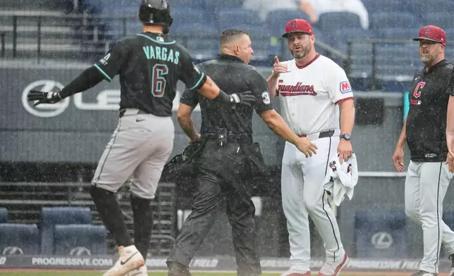 Home plate umpire Jonathan Parra (30) holds back Cleveland Guardians manager Stephen Vogt, center, from Arizona Diamondbacks' Ildemaro Vargas (6) during an argument in the sixth inning of a baseball game in Cleveland, Sunday, Aug. 2, 2026. (AP Photo/Sue Ogrocki)