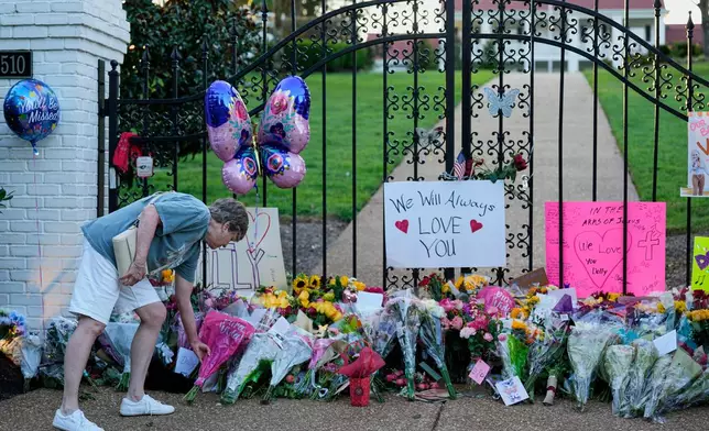 Becky Wangner leaves flowers for a makeshift memorial honoring Dolly Parton outside her home Tuesday, Aug. 25, 2026, in Brentwood, Tenn. (AP Photo/George Walker IV)