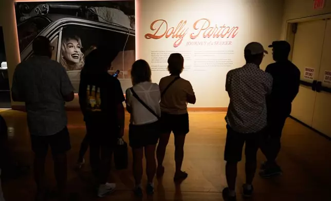 Guests visit the Dolly Parton exhibit at the Country Music Hall of Fame on Tuesday, Aug. 25, 2026, in Nashville. (AP Photo/George Walker IV)