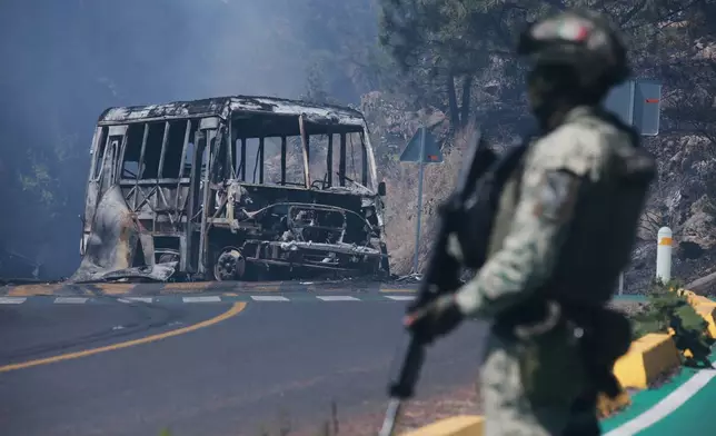 FILE - A soldier stands guard by a charred vehicle after it was set on fire in Cointzio, Michoacán state, Mexico, Feb. 22, 2026, following the death of the leader of the Jalisco New Generation Cartel, Nemesio Oseguera, also known as "El Mencho." (AP Photo/Armando Solis, File)