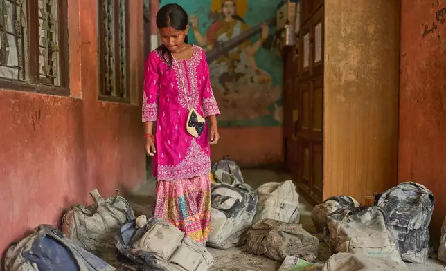 A student searches for her school bag from a pile extracted from the mud brought in by the recent flash floods, at the Shree Bagheswori Madhyamik School in Galchhi, Dhading district of Nepal Sunday, Aug. 30, 2026. (AP Photo/Niranjan Shrestha)