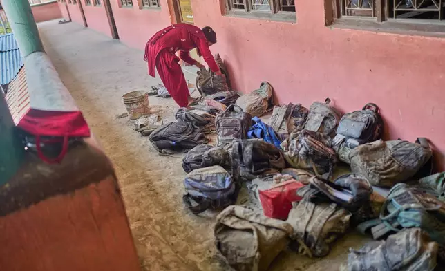 A mother searches for her child's bag from a pile extracted from the mud brought in by the recent flash floods, at the Shree Bagheswori Madhyamik School in Galchhi, Dhading district of Nepal Sunday, Aug. 30, 2026. (AP Photo/Niranjan Shrestha)
