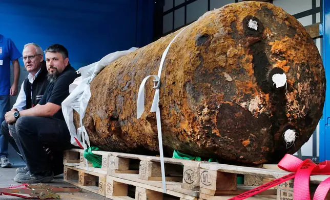 FILE - Members of a bomb disposal unit, Dieter Schwaetzler, left, and Rene Bennert sit next to 1.8 ton World War II bomb after defusing it in Frankfurt, Germany, Sept. 3, 2017. (AP Photo/Michael Probst, File)