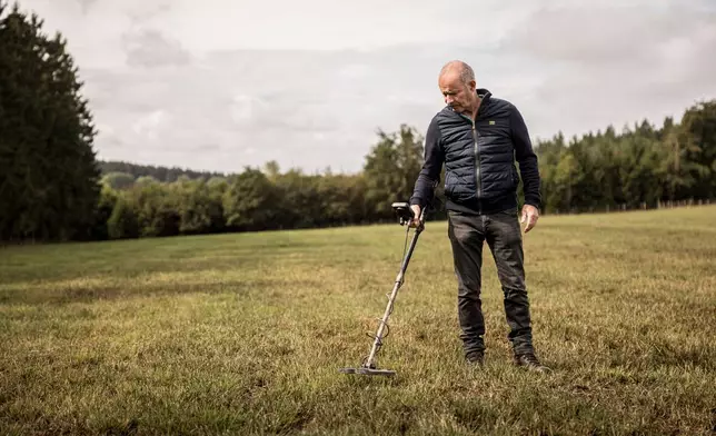 Bernard Collard runs a metal detector over a field in the Elsenborn area of Krinkelt, Belgium, Friday, Aug. 21, 2026. (AP Photo/Valentin Bianchi)