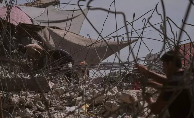 Palestinians remove iron from the rubble of buildings destroyed by Israeli airstrikes during the war with Hamas, repair and recycle it for construction, building tents or selling it, in Gaza City, Sunday, Aug. 16, 2026. (AP Photo/Jehad Alshrafi)