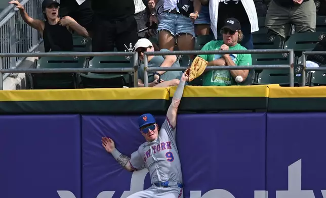 Fans, top, react as New York Mets center fielder A.J. Ewing (9) misses the winning solo home run hit by Chicago White Sox's Tristan Peters during the ninth inning of a baseball game in Chicago, Sunday, Aug. 23, 2026. (AP Photo/Paul Beaty)