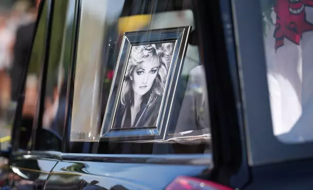 A hearse with the coffin and a picture of singer Bonnie Tyler moves through the streets past fans ahead of her funeral in Mumbles, Wales, Saturday, Aug. 15, 2026. (AP Photo/Alastair Grant)
