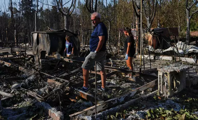 FILE - Maria del Carmen, left, her daughter Maria del Carmen Lopez, right, and her partner Mario Gonzalez, center, collect their belongings after their bungalows were ravaged by a wildfire at a campsite in Valle de Iruelas, Spain, July 30, 2026. (AP Photo/Manu Fernandez, File)