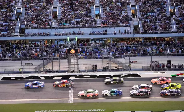 Kyle Larson (5) and Chase Briscoe (19) lead a group through the front stretch during early laps in the NASCAR auto race at Daytona International Speedway, Saturday, Aug. 29, 2026, in Daytona Beach, Fla. (AP Photo/John Raoux)