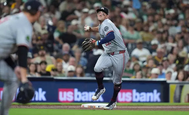 Minnesota Twins third baseman Brooks Lee throws to first too late as San Diego Padres' Austin Hays arrives safely with a single during the fifth inning of a baseball game Friday, Aug. 21, 2026, in San Diego. (AP Photo/Gregory Bull)