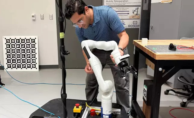 Nikhil Malhotra, co-founder of New Frontier Robotics, demonstrates his mobile manipulator robot arm in a lab at the University of Waterloo on July 8, 2026, in Waterloo, Ontario. (AP Photo/Kelvin Chan)