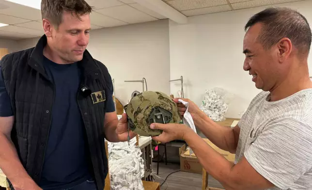 Wuxly CEO James Yurichuk and garment factory owner Aaron Lyand inspect military helmet covers on July 20, 2026, in North York, Ontario. (AP Photo/Kelvin Chan)