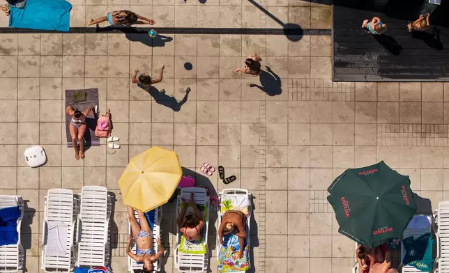An aerial view of people sunbathing and playing volleyball at the Dobrinja public pool, in Sarajevo, Bosnia, Thursday, Aug. 6, 2026. (AP Photo/Armin Durgut)