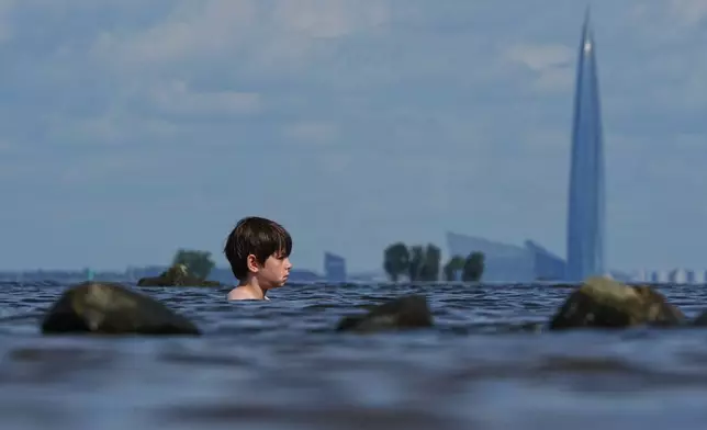 A boy bobs in the waters of the Gulf of Finland in St. Petersburg, Russia, Wednesday, Aug. 5, 2026, with the Lakhta Centre, the headquarters of Russian gas monopoly Gazprom, in the background. (AP Photo/Dmitri Lovetsky)