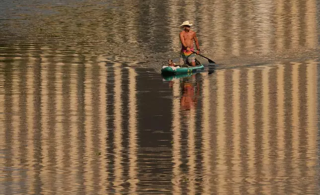 A man and his dog move along Lady Bird Lake on a paddle board in Austin, Texas, Wednesday, Aug. 5, 2026. (AP Photo/Eric Gay)