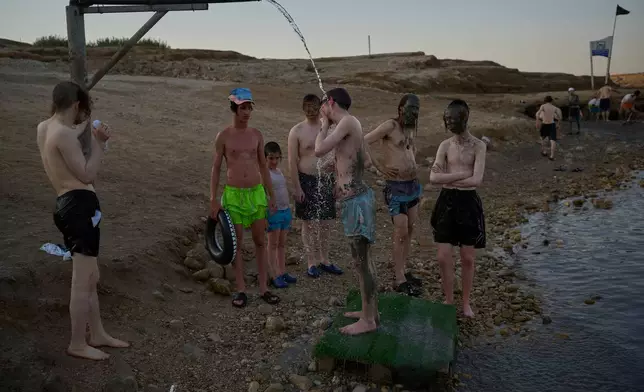 Ultra-Orthodox Jewish men wash mud off themselves after covering their bodies with it at the Dead Sea in the West Bank, Monday, Aug. 3, 2026. (AP Photo/Ohad Zwigenberg)