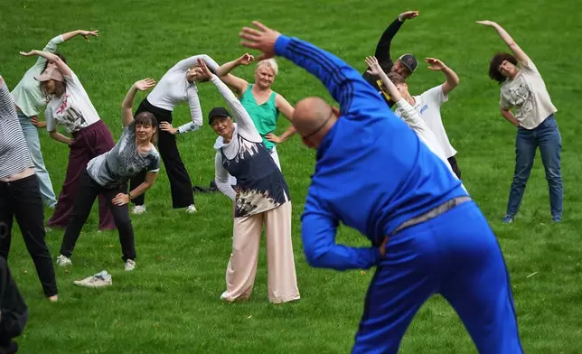 People exercise in a park marking Physical Training Enthusiast's Day in St. Petersburg, Russia, Tuesday, Aug. 4, 2026. (AP Photo/Dmitri Lovetsky)