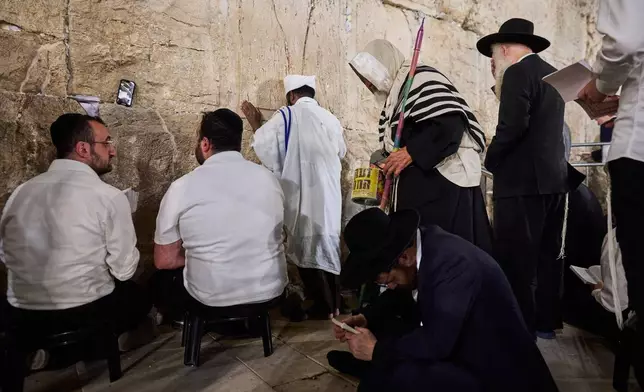 Ultra-orthodox Jewish men pray during the mourning ritual of Tisha B'Av at the Western Wall, Judaism's holiest site, in Jerusalem's Old City, Wednesday, July 22, 2026. (AP Photo/Ohad Zwigenberg)