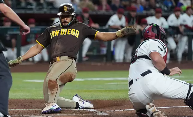 San Diego Padres' Fernando Tatis Jr., left, socres a run ahead of a tag by Arizona Diamondbacks catcher James McCann during the second inning of a baseball game, Tuesday, Aug. 4, 2026, in Phoenix. (AP Photo/Ross D. Franklin)
