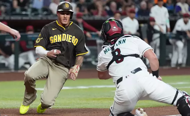 San Diego Padres' Manny Machado, left, scores a run as Arizona Diamondbacks catcher James McCann, right, loses the baseball during the first inning of a baseball game, Tuesday, Aug. 4, 2026, in Phoenix. (AP Photo/Ross D. Franklin)