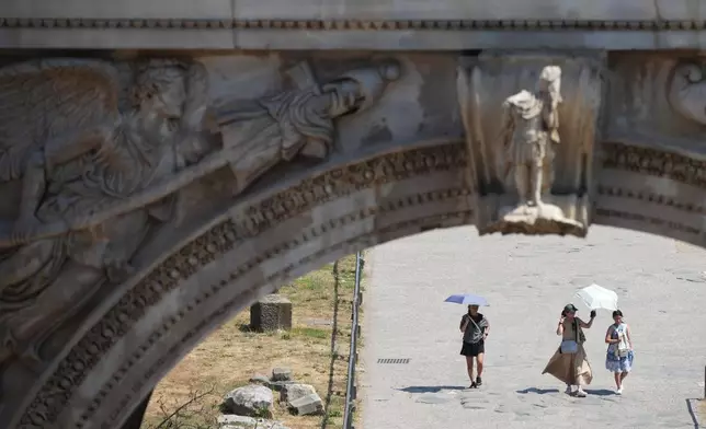 Tourists use umbrellas for shade as they visit Rome's ancient Forum, Saturday, Aug. 1, 2026. (AP Photo/Alessandra Tarantino)