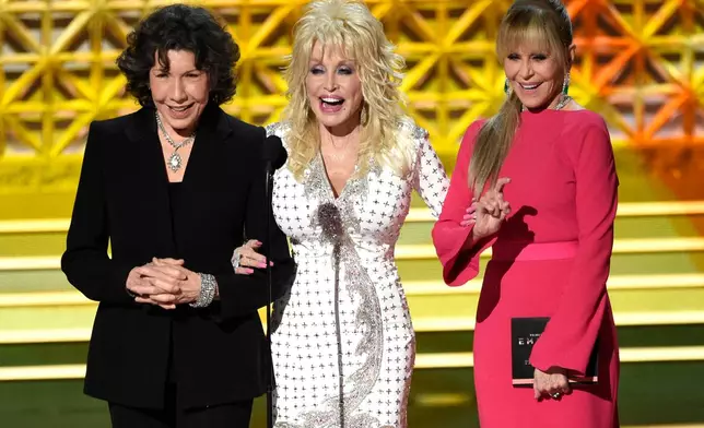 FILE - Dolly Parton, center, stands on stage with Lily Tomlin, left, and Jane Fonda at the 69th Primetime Emmy Awards in Los Angeles, Sept. 17, 2017. (Photo by Chris Pizzello/Invision/AP)