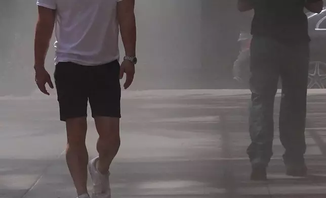 Pedestrians try to stay in the shade was they walk through misting machines at an outdoor mall, Friday, July 31, 2026, in Scottsdale, Ariz. (AP Photo/Ross D. Franklin)