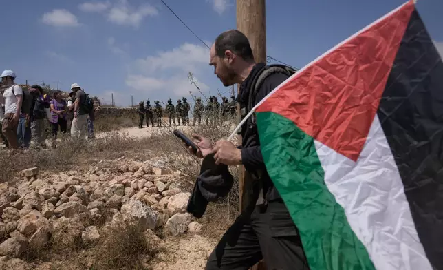 Israeli army soldiers turn back activists who marched with food and water supplies toward the houses of three Palestinian families that have been besieged by Israeli settlers for six days, in the occupied West Bank village of Qusra, south of Nablus, Friday, Aug. 14, 2026. (AP Photo/Majdi Mohammed)