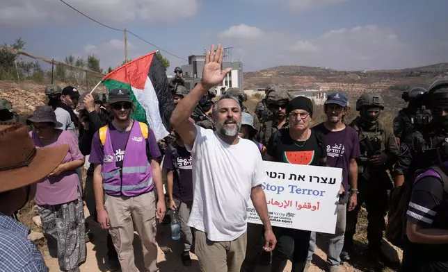 Activists march with food and water supplies toward the houses of three Palestinian families that have been besieged by Israeli settlers for six days, in the occupied West Bank village of Qusra, south of Nablus, Friday, Aug. 14, 2026. (AP Photo/Majdi Mohammed)