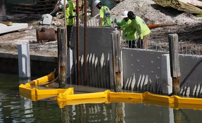 Workers install a 3D-printed living seawall manufactured by Kind Designs at the Church by the Sea, Tuesday, Aug. 4, 2026, in Fort Lauderdale, Fla. (AP Photo/Lynne Sladky)