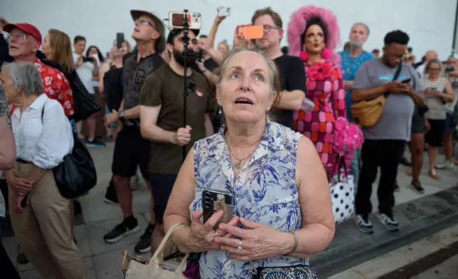 FILE - A crowd sings, "God Bless America," as they wait to watch the removal of President Donald Trump's name from the John F. Kennedy Center for the Performing Arts in Washington, June 12, 2026. (AP Photo/Cliff Owen, File)