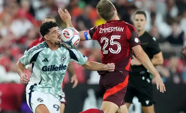 New England Revolution offense Dor Turgeman (99) takes the ball to the face as he pushes Toronto FC defense Walker Zimmerman (25) away during the second half of an MLS soccer game in Toronto, Saturday, Aug. 15, 2026. (Nathan Denette/The Canadian Press via AP)