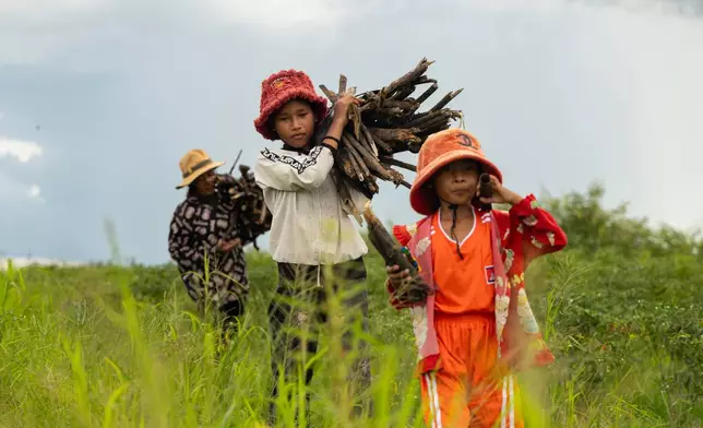 Sou Sreynich, center, collects firewood with her mother and sister near their home in a floating village on Cambodia's Tonle Sap Lake on Monday, June 29, 2026. (AP Photo/Anton L. Delgado)