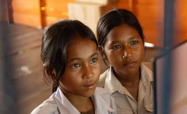 Thirteen-year-old Sou Sreynich, right, attends a computer class at a school in one of the floating villages of Cambodia's Tonle Sap Lake on Monday, June 29, 2026. (AP Photo/Anton L. Delgado)
