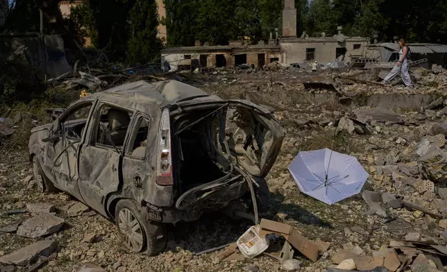 A local resident walks past destroyed vehicles and scattered debris the day after a Russian missile and drone attack in Kyiv, Friday, Aug. 21, 2026. (AP Photo/Francisco Seco)