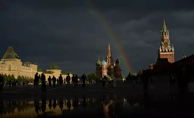 People enjoy a nice view on rainbow, backdropped by the GUM state shop, left, the St. Basil's Cathedral, center, and the Spasskaya Tower, right, walking in Red Square during the golden hour in Moscow, Russia, on Monday, Aug. 24, 2026. (AP Photo/Alexander Zemlianichenko)