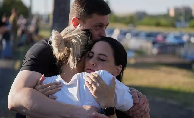 People embrace each other near a burning shopping mall following a Russian drone attack in Kryvyi Rih, Ukraine, Friday, Aug. 21, 2026. (AP Photo)
