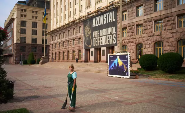 A street cleaner observes a daily nationwide minute of silence in memory of soldiers killed in the war with Russia, in Kyiv, Tuesday, Aug. 18, 2026. (AP Photo/Francisco Seco)